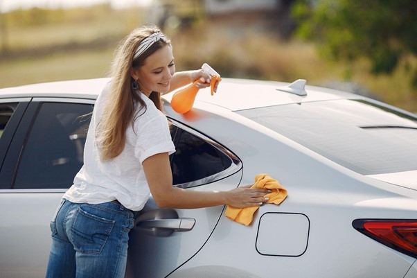 жена почиства с кърпа и препарат кола