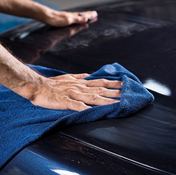 човек с кърпа полира автомобил